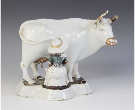 An unusual 18th/19th century tin glazed Delft pottery study of a seated milkmaid and her cow, showing traces of polychrome en