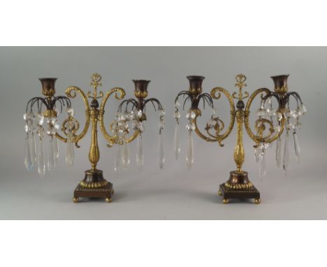 A pair of bronze and gilt bronze twin branch candelabra, 19th century, each with scrolling lustre hung arms, terminating in u