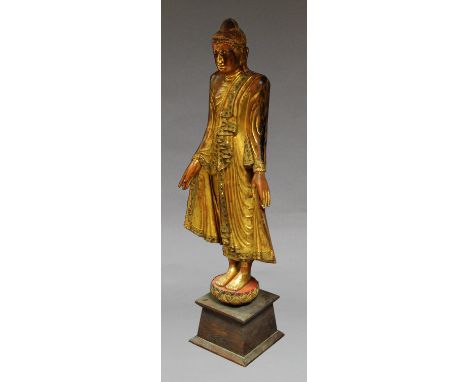 A Burmese gilt wood model of a standing Buddha, wearing a bejewelled robe, standing on a lotus flower, on a later base, overa