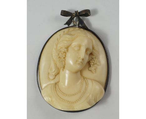 A Victorian ivory portrait plaque of a young woman, her hair plated and braided, filled with grapes and vine leaves, with bea