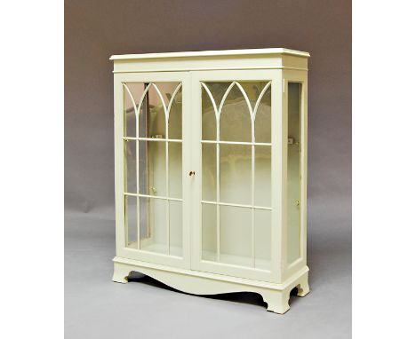 A painted rectangular bookcase, glazed Gothic doors, on bracket feet, 107cm high x 87cm wide x 31cm deep.  
Provenance; Bally