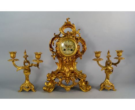 A French ormolu mantel clock garniture, late 19th century, the waisted case overall moulded with acanthus scrolls, on scrolli