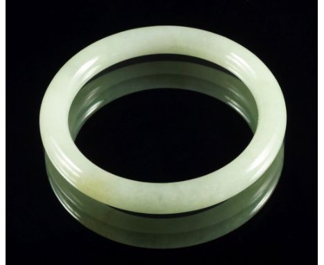 A Chinese apple green jade bangle, of circular form, 6.75cm diam 