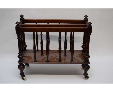 Small Victorian mahogany magazine rack with spindle turned supports and raised on brass and ceramic casters, 44cm wide