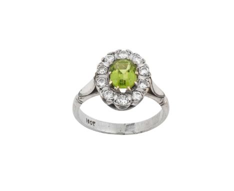 A Peridot and Diamond Cluster Ringthe emerald-cut peridot within a border of round brilliant cut and eight-cut diamonds, in w