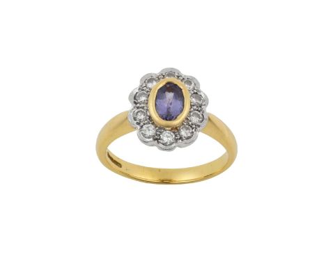 An 18 Carat Gold Tanzanite and Diamond Cluster Ringthe oval cut tanzanite in a yellow rubbed over setting, within a border of