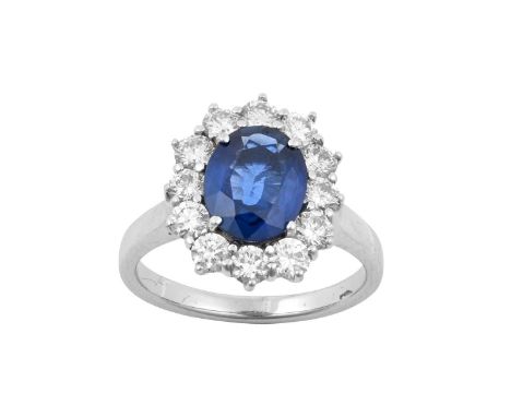 A Sapphire and Diamond Cluster Ringthe oval cut sapphire within a border of round brilliant cut diamonds, in white claw setti