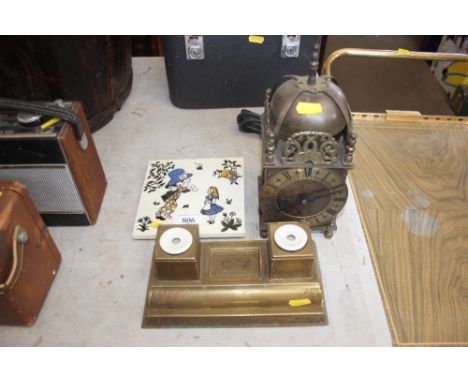 A tile depicting Alice in Wonderland; a brass lantern clock and a brass desk stand
