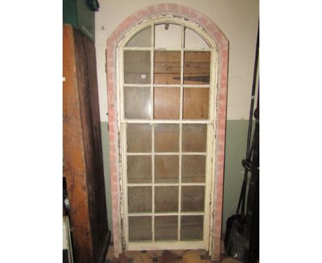 A reclaimed pine framed casement window of arched form with segmented rectangular glazed panels and opening light together wi