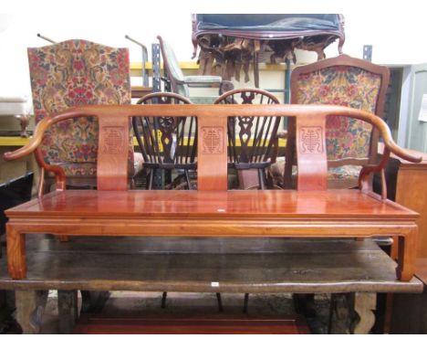 A substantial Chinese hardwood bench, the shaped splat back with carved geometric detail and set within scrolled arms, with s