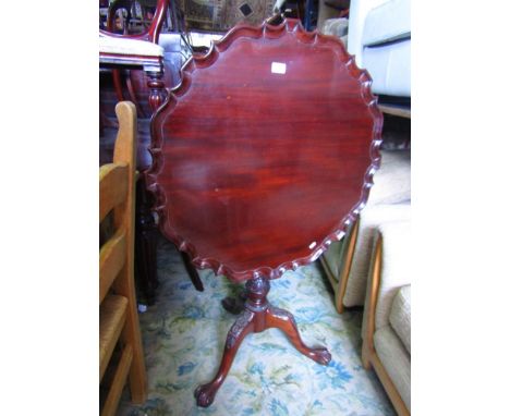 A Georgian style mahogany supper table with piecrust border raised on a turned pillar and tripod with carved detail.