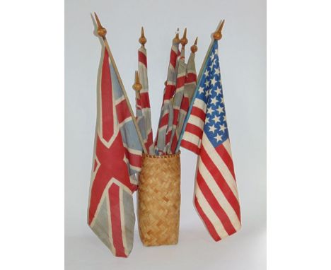 A collection of vintage flags, mainly Union Jacks, within a wicker basket.
