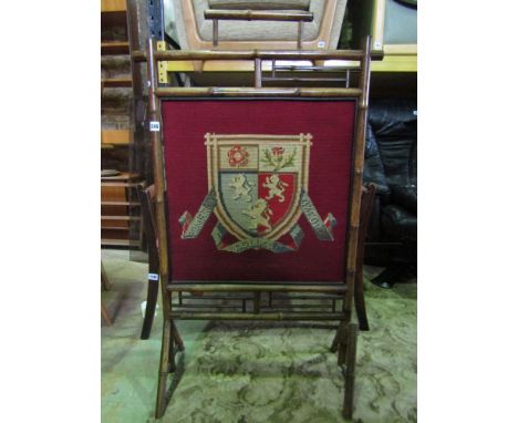 A Victorian bamboo fire screen incorporating a hand worked tapestry panel showing the coat of arms for Pembroke College Oxfor