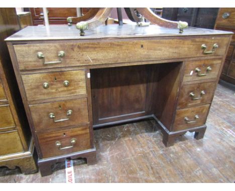 A Georgian mahogany kneehole writing desk fitted with seven drawers and central cupboard with original brass fittings on brac