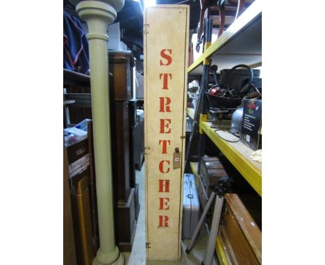 A vintage upright cupboard painted and stencilled three times with the word 'Stretcher' enclosing an original emergency stret