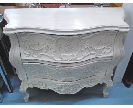 BOMBE COMMODE, distressed effect cream painted, with carved detail and two drawers, 113cm W x 47cm D x 90cm H.