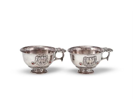 A pair of Mongolian silver cups, 19th century, with lion form ring handle, the body applied with matching lion head design an