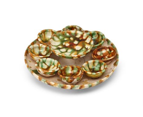 A set of Chinese sancai glazed wine cups and tray, Tang Dynasty (618-907), the rim of the trays splashed with a green, ochre 