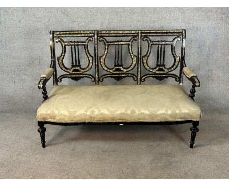 A 19th century ebonised and mother of pearl three seater pierced splat back open arm settee raised on turned supports. H. 88c