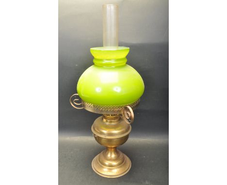 An early 20th century circa 1920’s brass oil lamp. The lamp having a green mushroom shape light shade, twin adjustable wick r