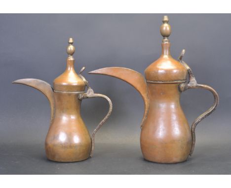 Two 20th century copper and brass Middle Eastern Dallah coffee pot. The two graduated pots having hinged lid with brass finia