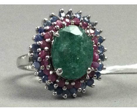 EMERALD, RUBY AND SAPPHIRE RING,the 8.20 carat emerald within a halo of rubies and sapphires, in silver, size N