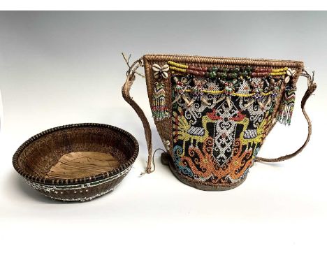 A Dayak baby carrier, Borneo, the woven cane body with an applied beadwork panel depicting stylised birds and hung with furth