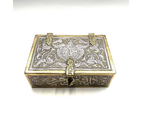 A Cairoware brass and silver inlaid box, circa 1900, with fixed wooden liners, the hinged cover with a central palmette enclo