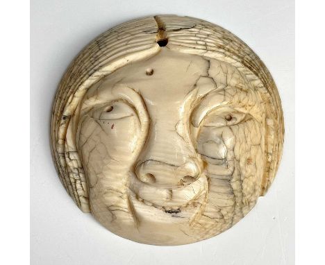A Japanese netsuke portraying a smiling Okame mask, 19th century, diameter 5.3cm.