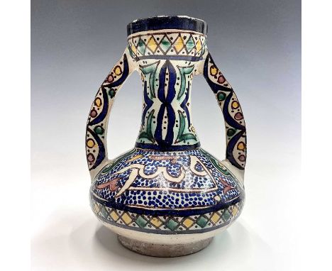 A Moroccan pottery twin-handled vase, mid 20th century, with calligraphy and geometric motifs, height 21.5cm, width 17cm.