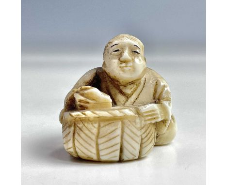 A Japanese ivory netsuke of a seated figure with basket, Meiji period, signed, height 3cm, width 3cm.