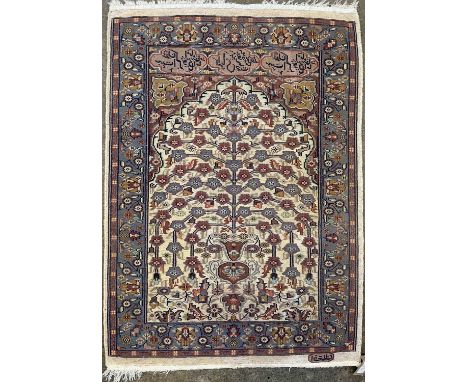 A Persian design prayer rug, mid 20th century, the ivory mihrab with a stylised tree and foliage, below three cartouches encl