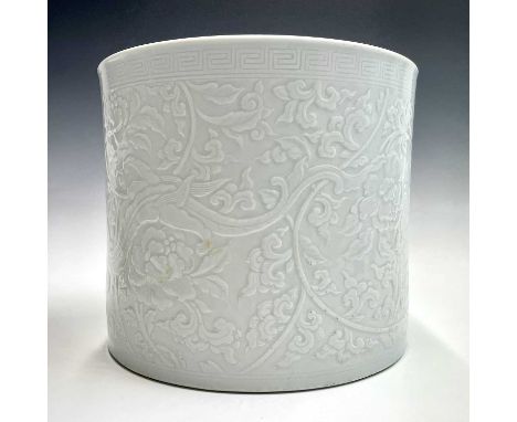 A large Chinese blanc de chine brush pot, 20th century, decorated with scrolling tendrils, flowerheads and stylised dragons, 