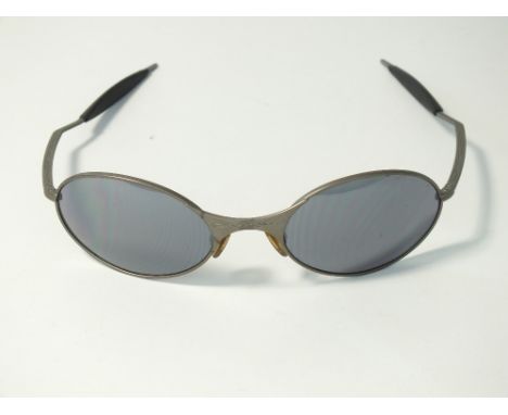 A pair of Oakley sunglasses, oval titanium style frame with smoke mirror lenses