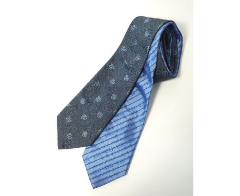 Two Gucci ties, one light blue with dark blue Gucci G pattern, one dark grey with Gucci G and spiral dot pattern in grey