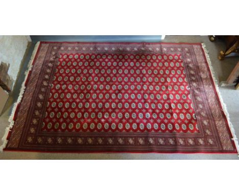 A Large Bokhara Woollen Carpet with nine rows of guls upon a wine red ground within multiple borders, 300 x 198cm 