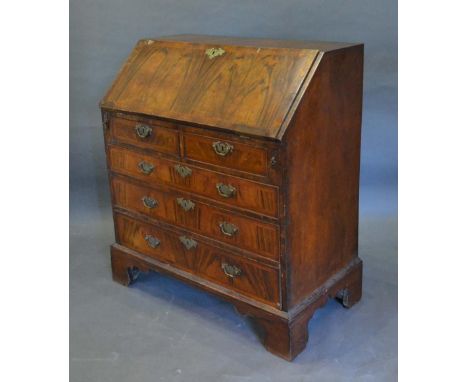 A George I Walnut Bureau, the fall front enclosing a fitted interior with pigeonholes and drawers above two short and three l