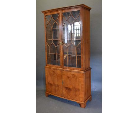 A 20th Century Bow-Fronted Display Cabinet, the moulded cornice above two astragal glazed doors enclosing shelves, the lower 