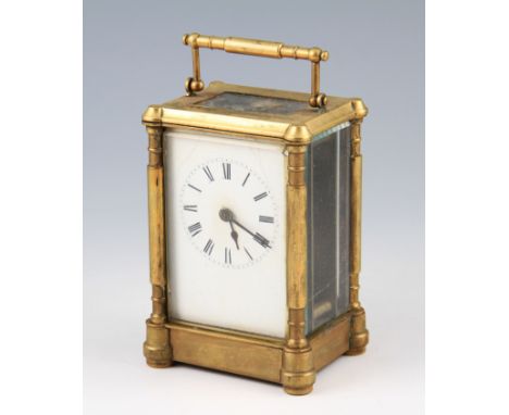 An early 20th Century brass carriage clock with shaped supports, the white enamel face having black Roman numeral hourly mark
