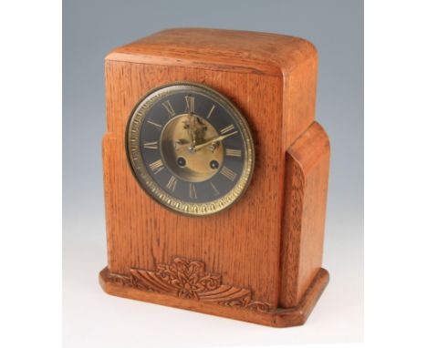 An Art Deco oak cased mantel clock having stepped design to sides plus carved decoration to the lower front, the face having 