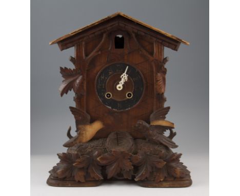 An early 20th Century Black Forest carved wooden cuckoo mantel clock with birds and foliage decoration with black chapter rin