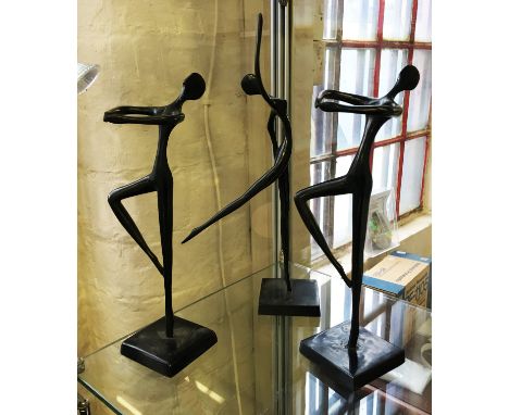 A group of three stylised bronze figures depicting female nudes.