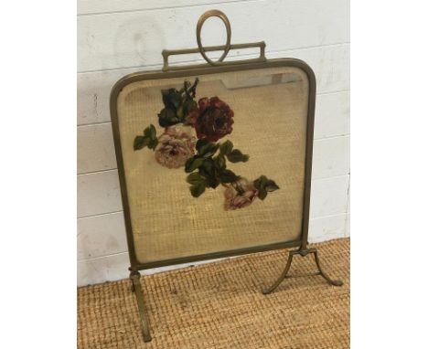 An Art Nouveau brass framed fire screen with a painted floral mirrored panel 