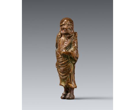Netsuke eines Fremden mit Schwert am Rücken. Nadelholz mit Resten einer Farbfassung (saishiki). 19. Stehend mit besonders lan