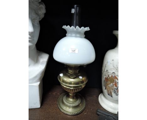 A brass based oil lamp having a milk glass shade