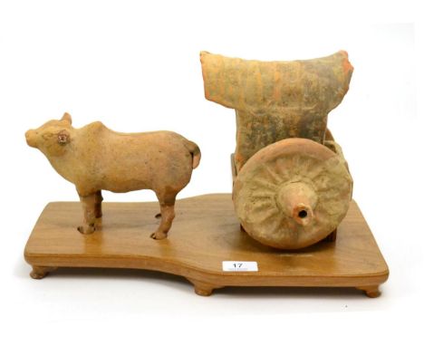 A Chinese Tang Dynasty  pottery statue of an ox and cart, circa 618-907 A.D, modelled in the round and raised upon museum woo