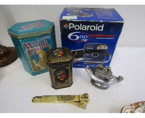 A polaroid camera, vintage tins, table lighter and cigar cutter