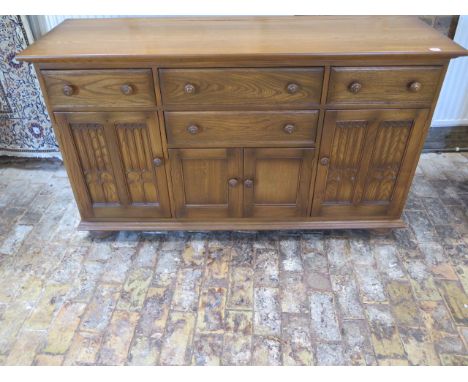 An Ercol elm gothic style Canterbury dresser base with 4 drawers and 4 cupboard doors, 90cm tall x 155cm x 52cm, some usage m