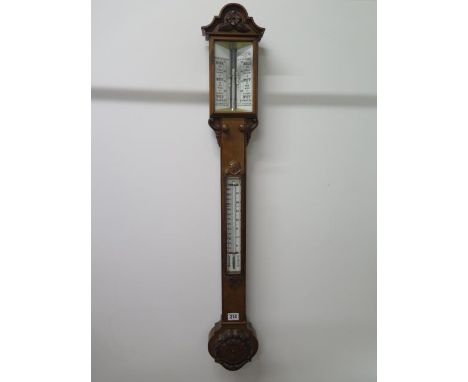 A late 19th century oak cased stick barometer with foliate carved embellishments, ivory plate and thermometer to the mid sect