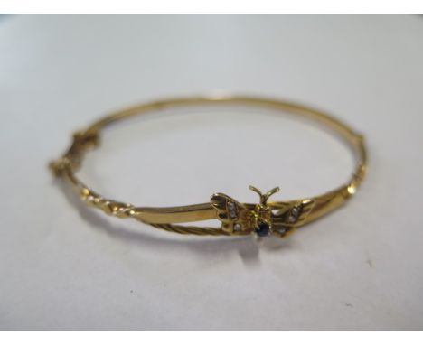 A continental yellow gold hinged bangle with sapphire and pearl set butterfly, external 6cm x 5cm, approx 3.7 grams, in good 